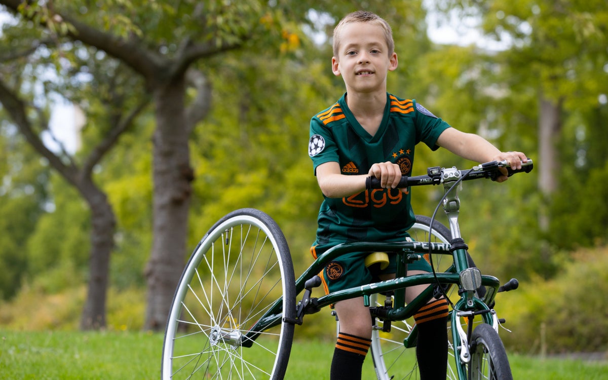 Jongen met cerebrale parese zit op een fiets