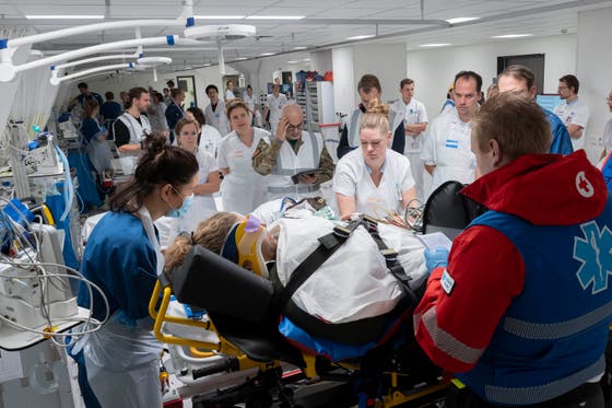 Een groep mensen in een kamer met een persoon op een brancard