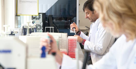 Een man in een labjas die een pipet vasthoudt