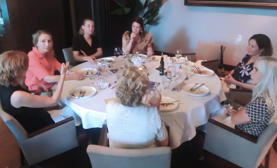 Een groep mensen die rond een tafel zit