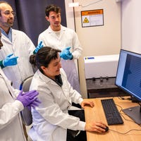 Een groep mensen in laboratoriumjassen kijkt naar een computer