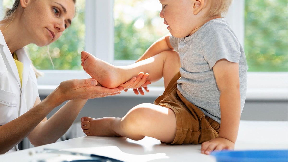 Een vrouw die het voetje van een baby vasthoudt