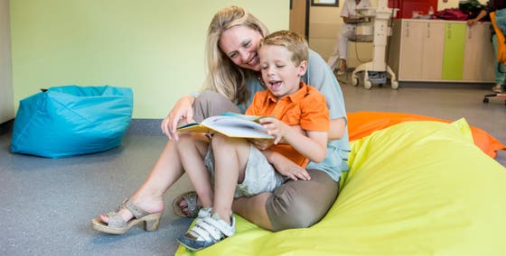 Vrouw heeft kind op schoot en ze lezen samen een boek