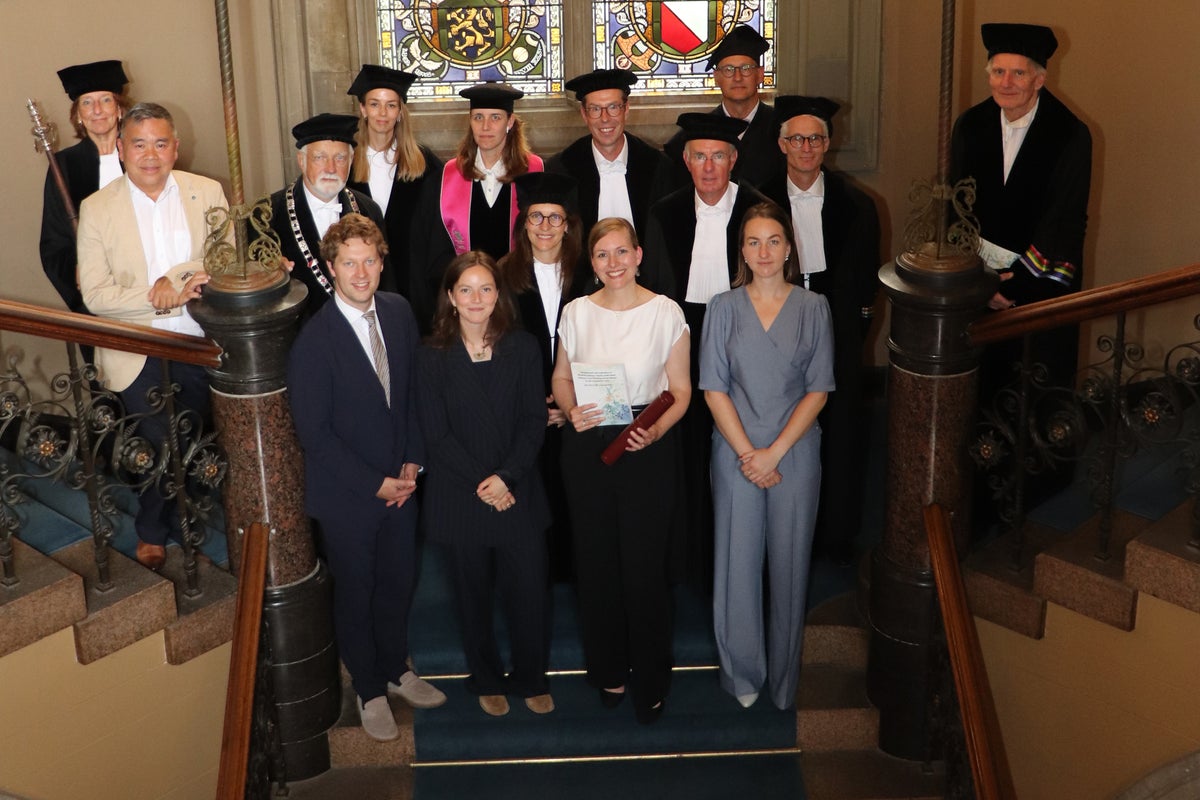 Een groep mensen in afstudeergewaden en -hoeden die op een trap staan