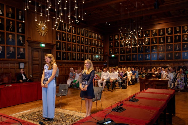 Twee vrouwen die op een podium staan voor een publiek