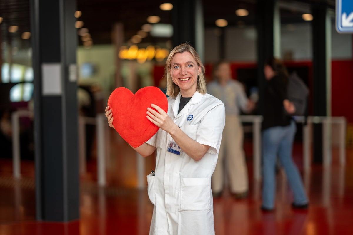 Een vrouw (Linda van Laake) in een witte jas met een rood hart.