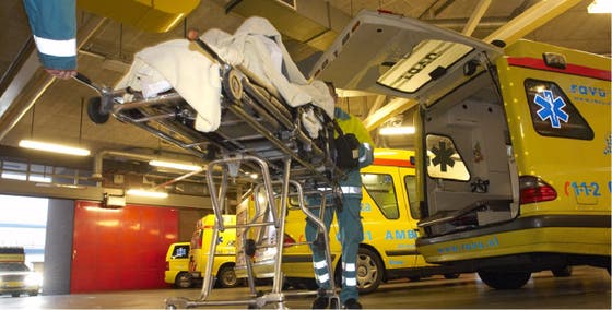 A patient on a mobile bed is being transferred to an ambulance.