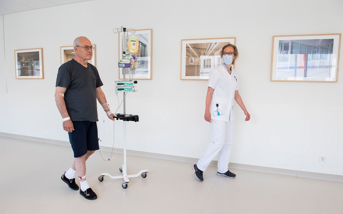 Patiënt met beweegsensor loopt samen met een fysiotherapeut