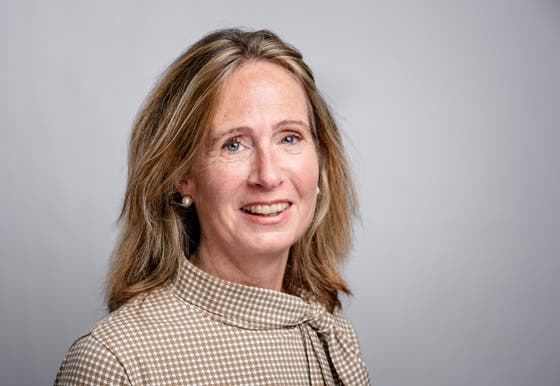 Rieke van der Graaf lachend op de foto voor een grijze achtergrond. 