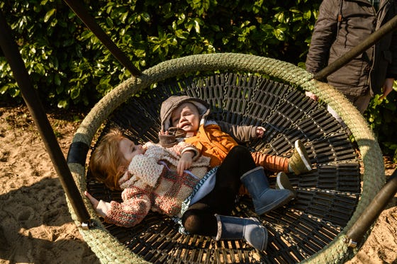 Twee kinderen liggen op een grote schommel