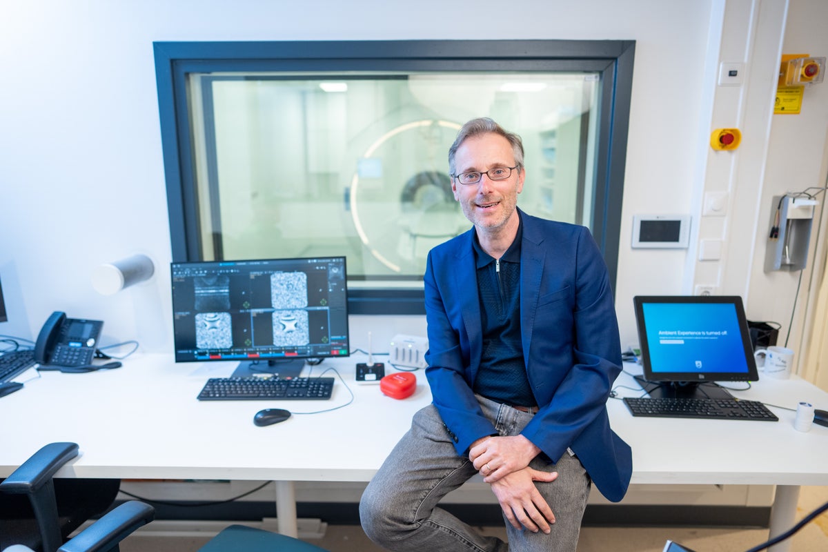 Alessandro Sbrizzi die op een bureau zit, voor een computerscherm met de MRI op de achtergrond