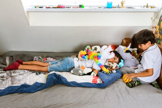 Twee kinderen spelen op een bed met knuffels