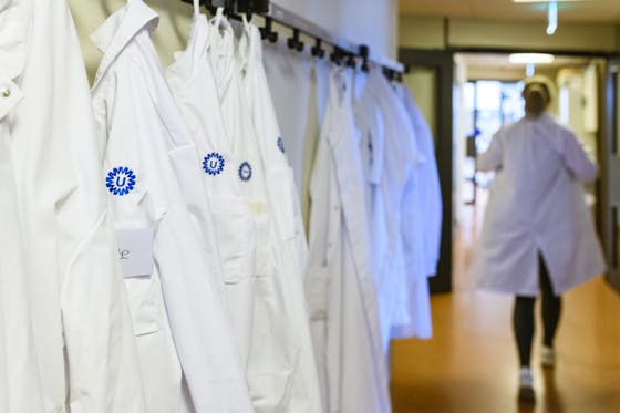 Laboratoruimjassen met het logo van het UMC Utrecht hangen in een gang.