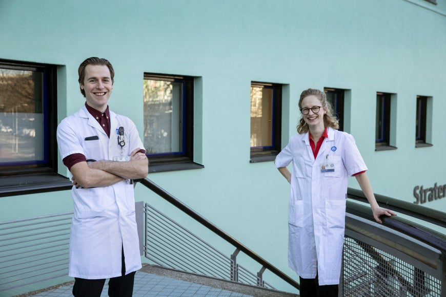 Een man en vrouw in laboratoriumjassen staan buiten een gebouw