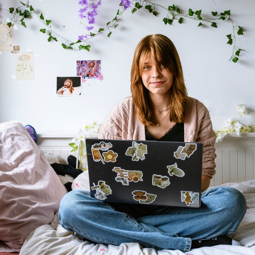 Maura heeft reuma. Ze zit op haar bed in haar slaapkamer, met een laptop op schoot.
