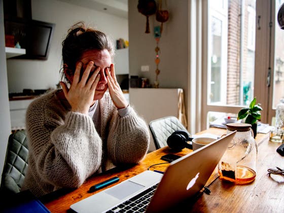 Een vrouw aan een tafel met haar handen op haar gezicht.