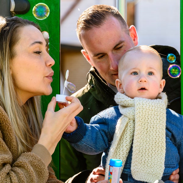 Ouders van baby Maxim blazen zeepbellen en Maxim volgt de bellen aandachtig