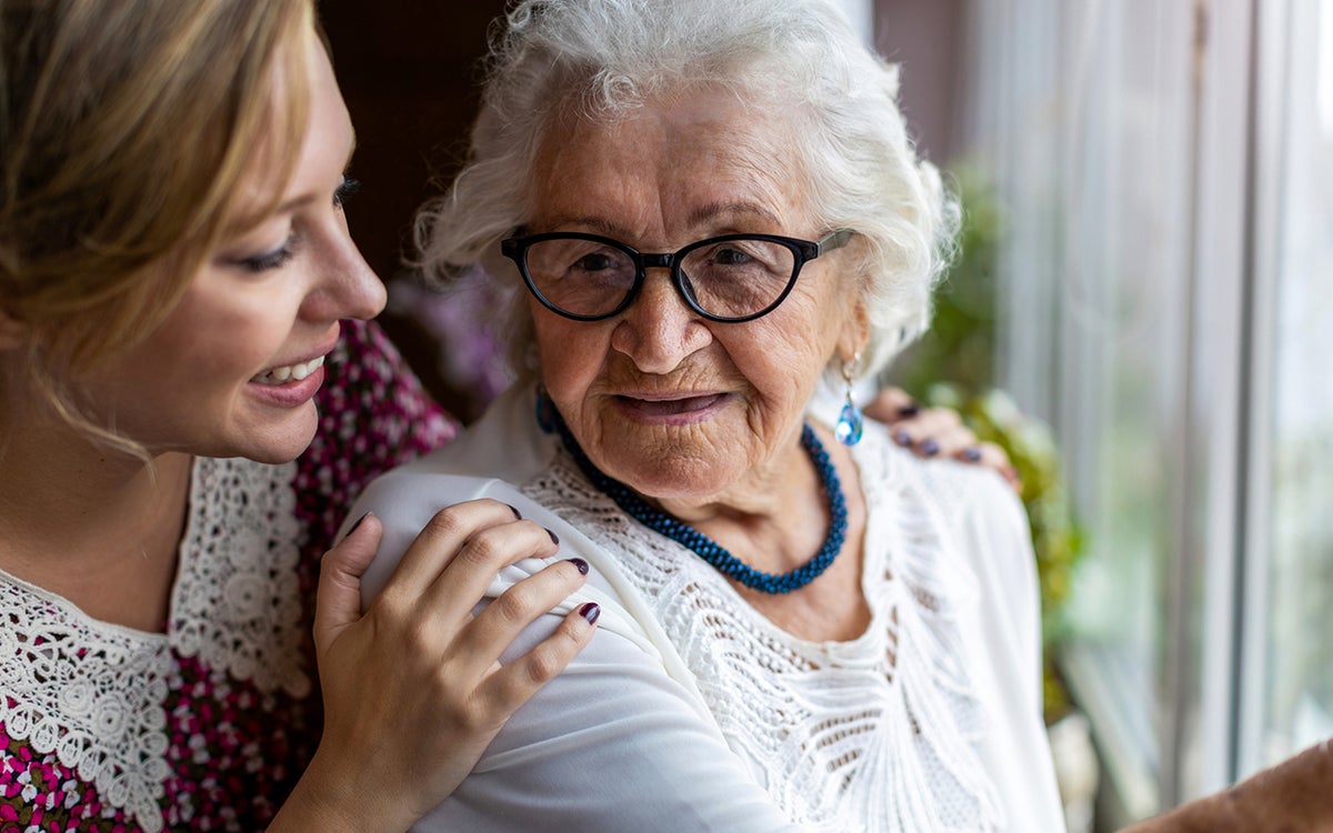 Een vrouw houdt een oude vrouw vast