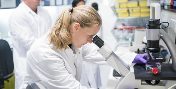 female researcher looking through a microscope