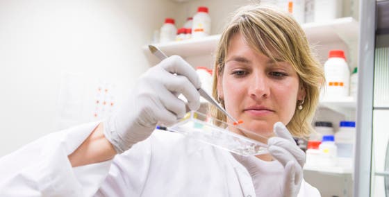 Een vrouw in een labjas die een pincet vasthoudt