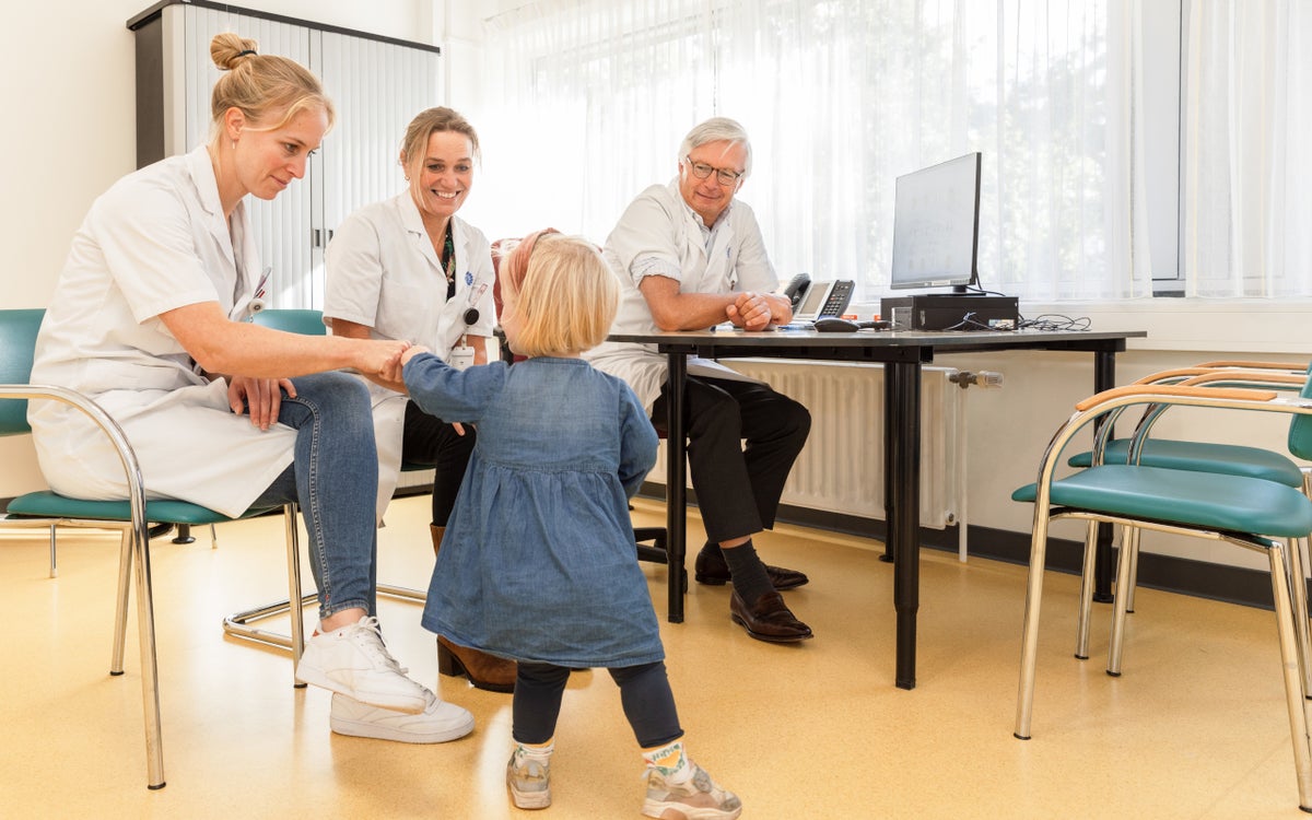 Peuter geeft een boks aan de regiebehandelaar. Twee andere zorgverleners kijken toe.